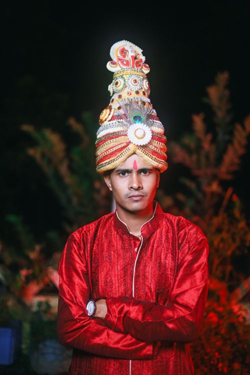 Free Portrait of a man in traditional Indian wedding clothing with an ornate headdress, standing confidently outdoors. Stock Photo