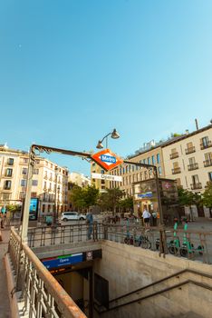 Sunny day at Opera Metro Station entrance in Madrid, capturing urban life and architecture.