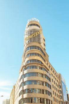 Historic Schweppes Building on Gran Vía, Madrid, under clear blue sky.