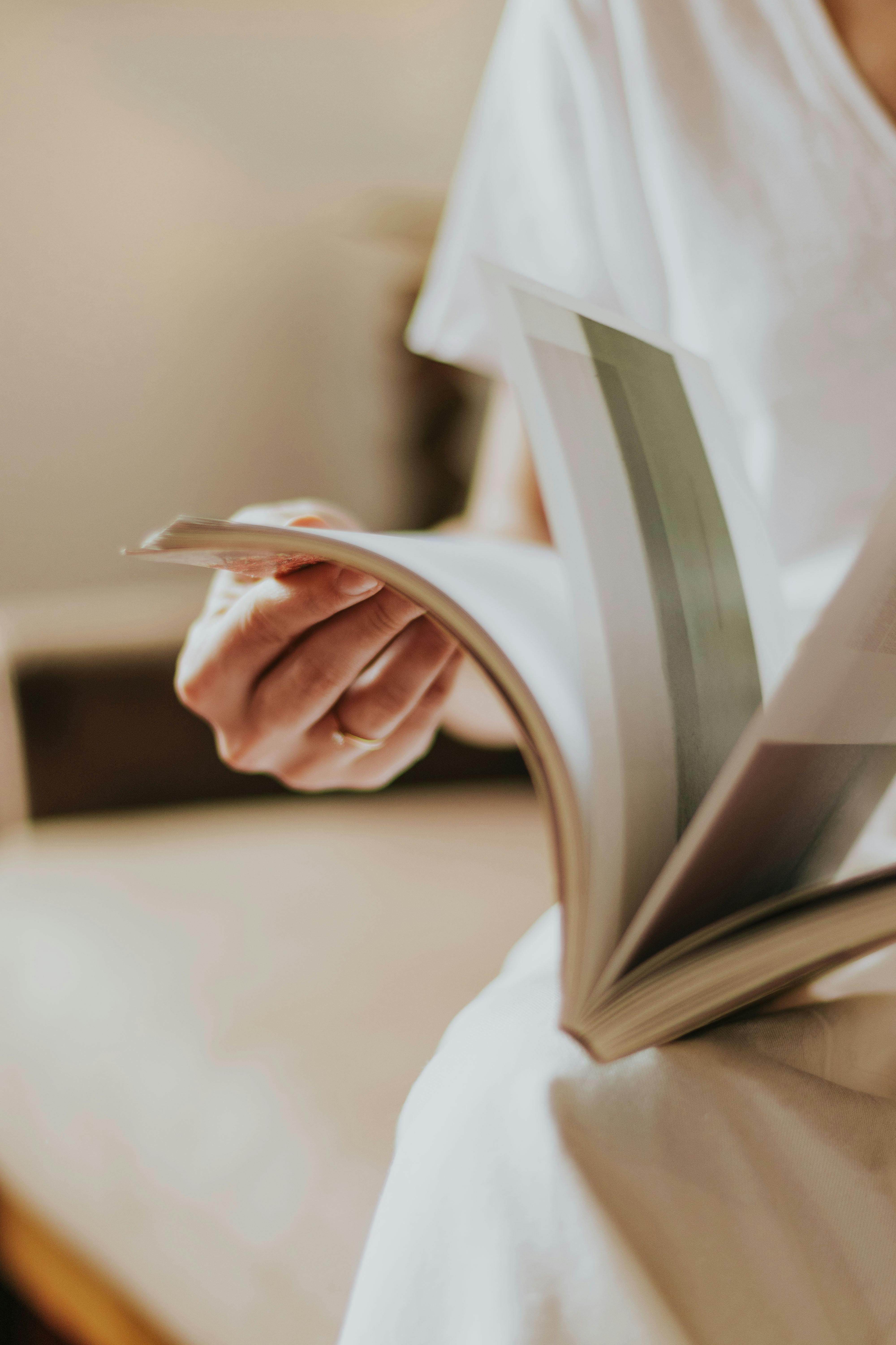 Close-up of a person reading a book indoors, highlighting relaxation and peace.