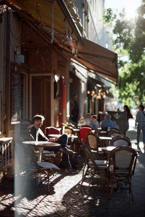 Free Sunny afternoon at an outdoor café with people sitting and enjoying a relaxed atmosphere. Stock Photo