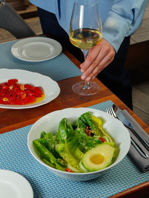 Free A person dining with fresh green salad and white wine, showcasing elegant dining setting. Stock Photo