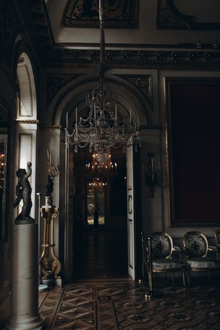 A beautifully ornate interior of a historic palace in Warsaw, featuring chandeliers and classic decor.