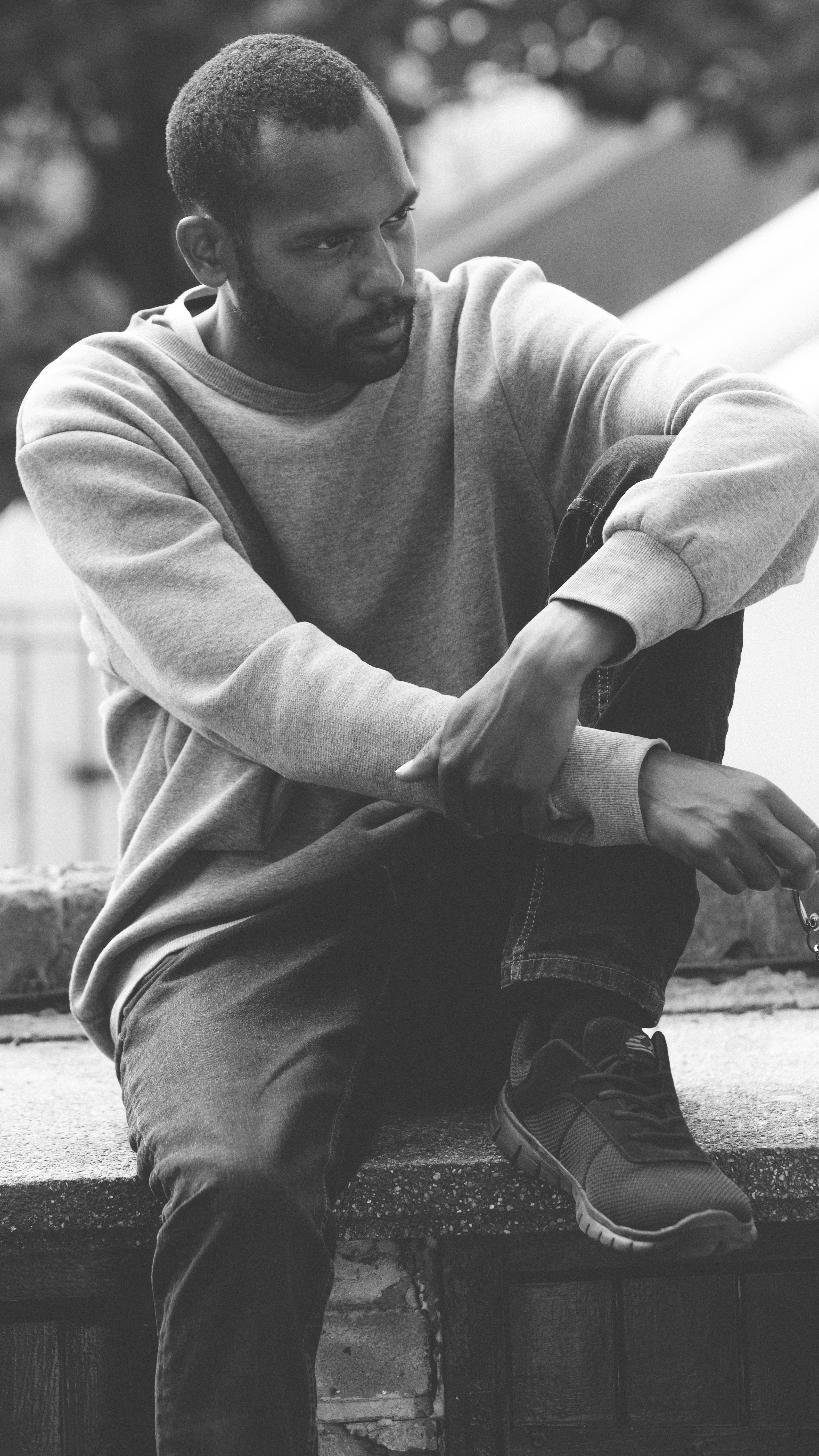 African Man Sitting on Wall in Black and White · Free Stock Photo