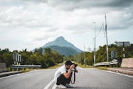 男子在宁静的山路上拍照，捕捉自然美景