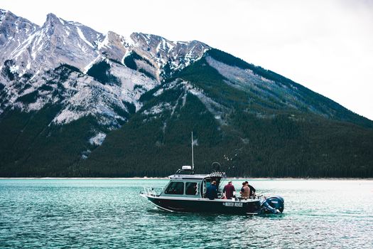 A boat with people enjoying a scenic ride on a lake in Banff National Park, surrounded by mountains.