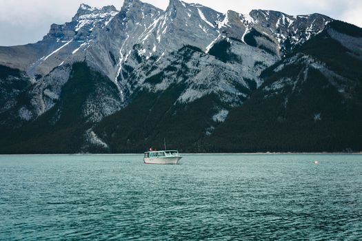 A serene lake in Banff with a boat and mountainous backdrop showcasing pristine nature.
