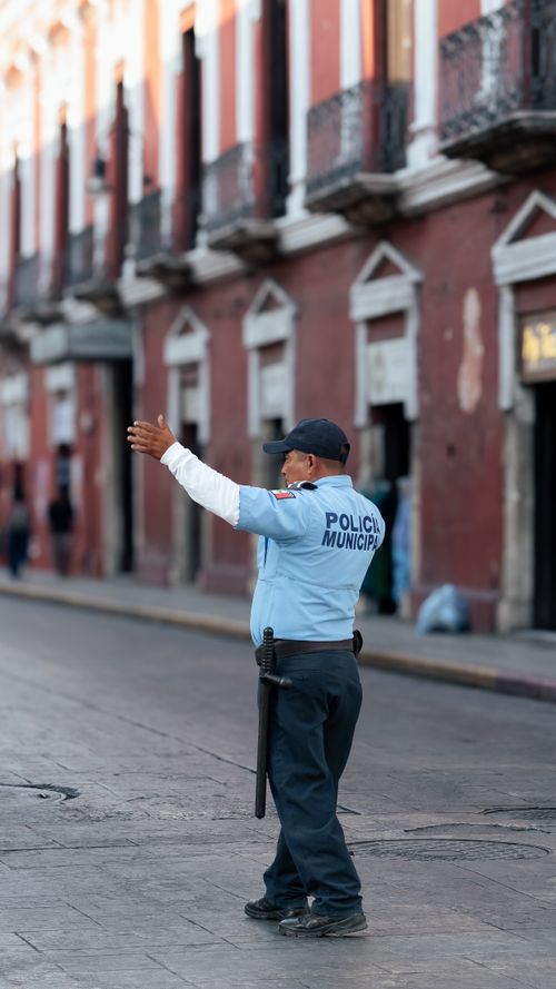 Free A municipal policeman directs traffic on a city street with historic architecture. Stock Photo