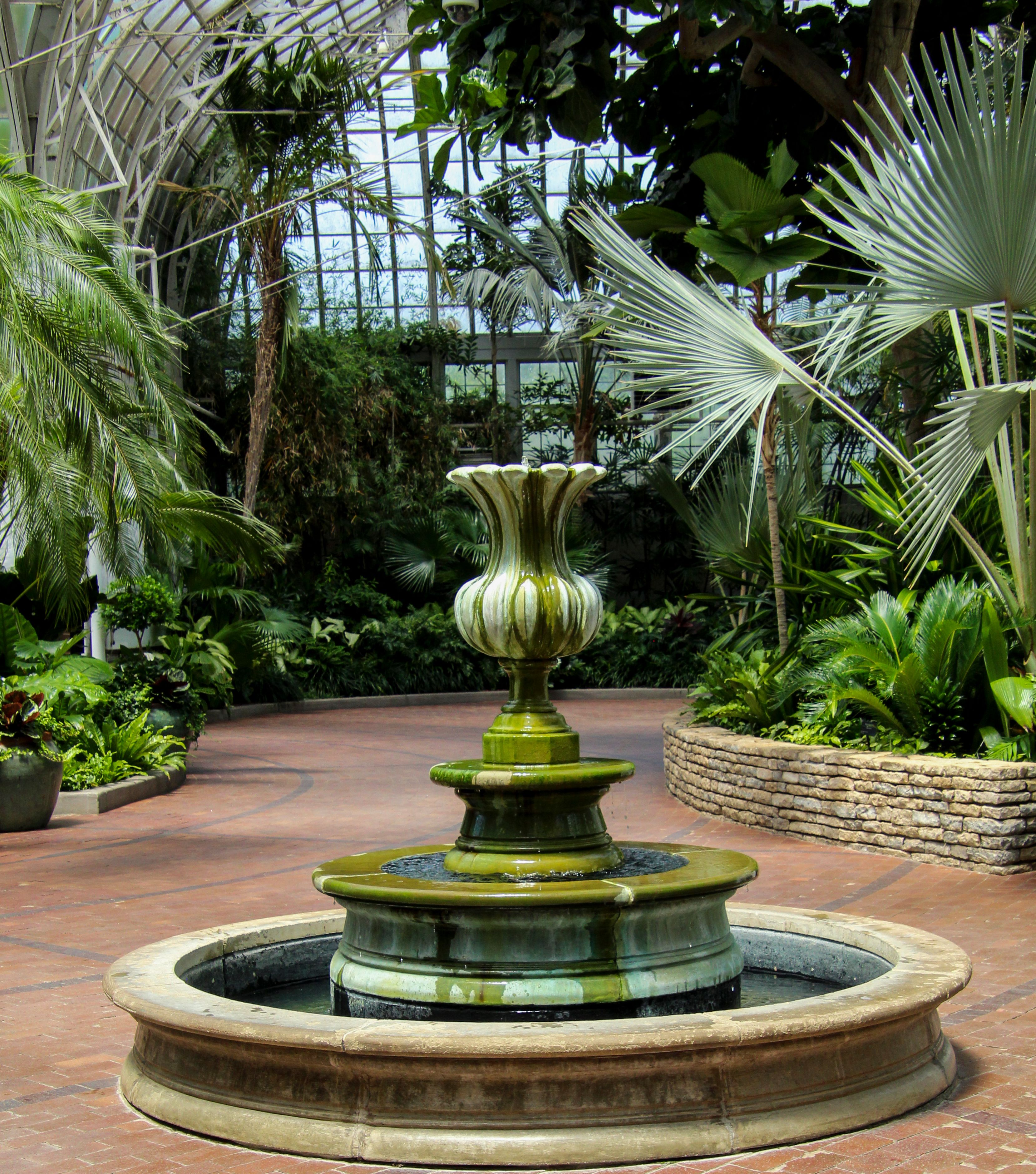 A fountain in a garden surrounded by palm trees · Free Stock Photo
