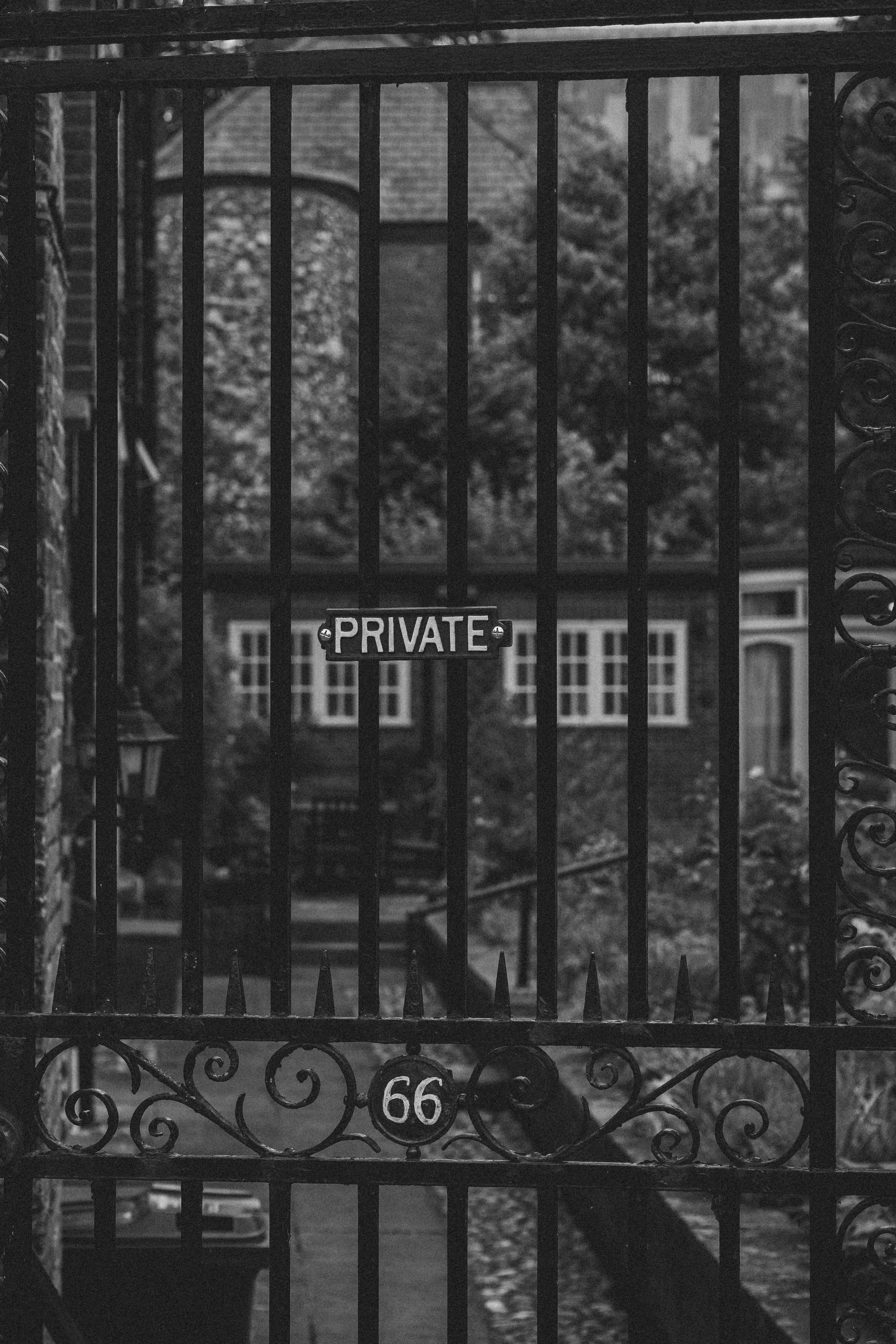 Black and white photo of a wrought iron gate with 'PRIVATE' sign and number 66.