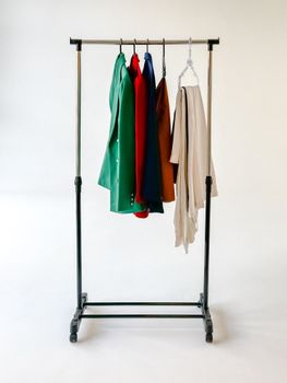 A vibrant collection of clothing on a wheeled garment rack in a minimalist setup.