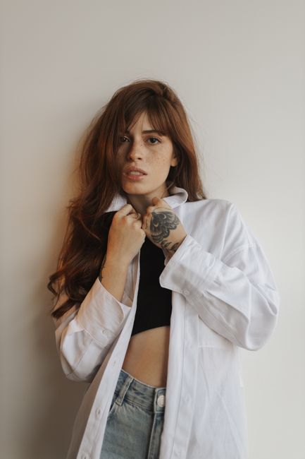 Fashion model in a white blouse and black top posing with confidence in a stylish indoor setting.