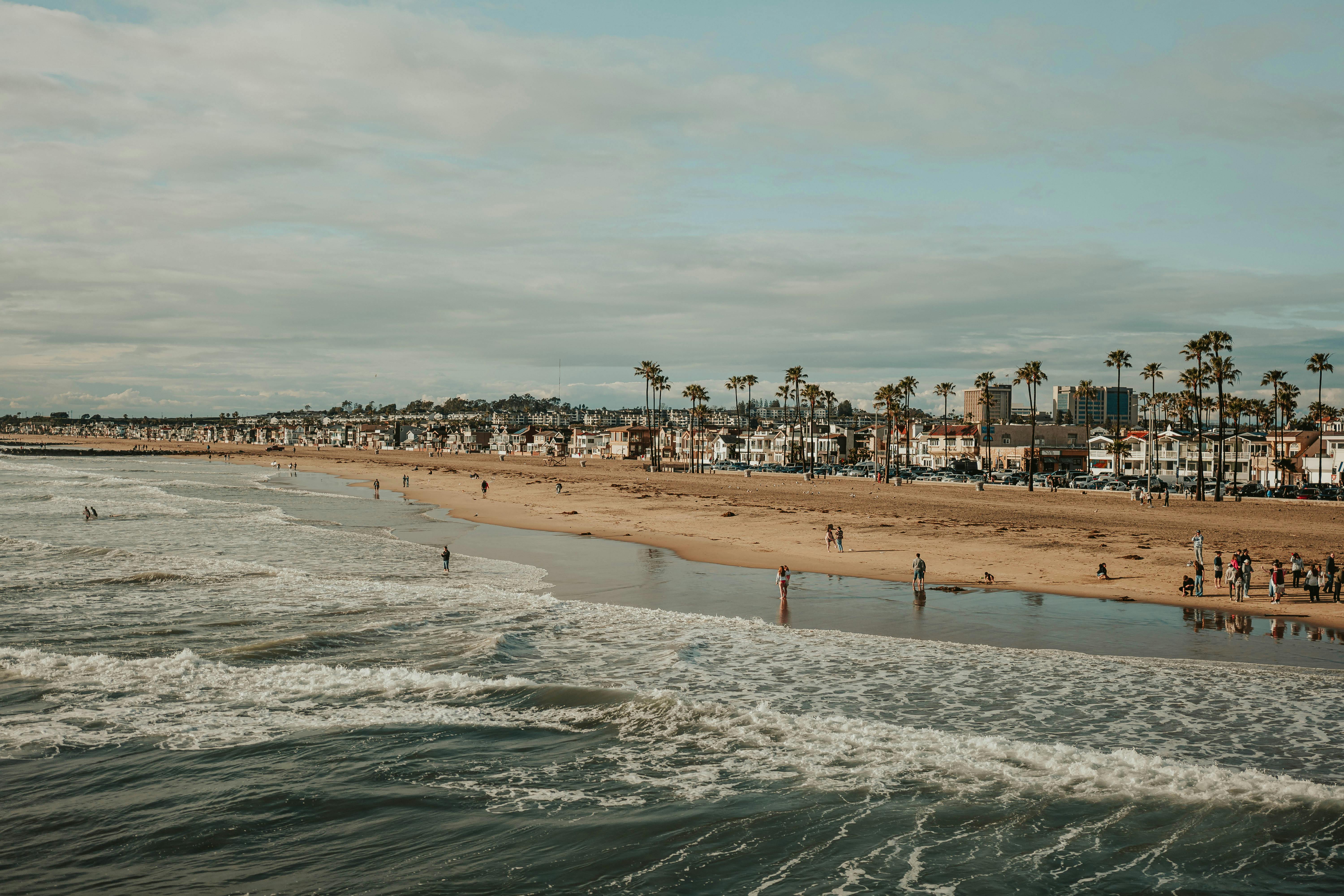 Stunning aerial view of a lively beachfront with palm trees and cityscape in the background