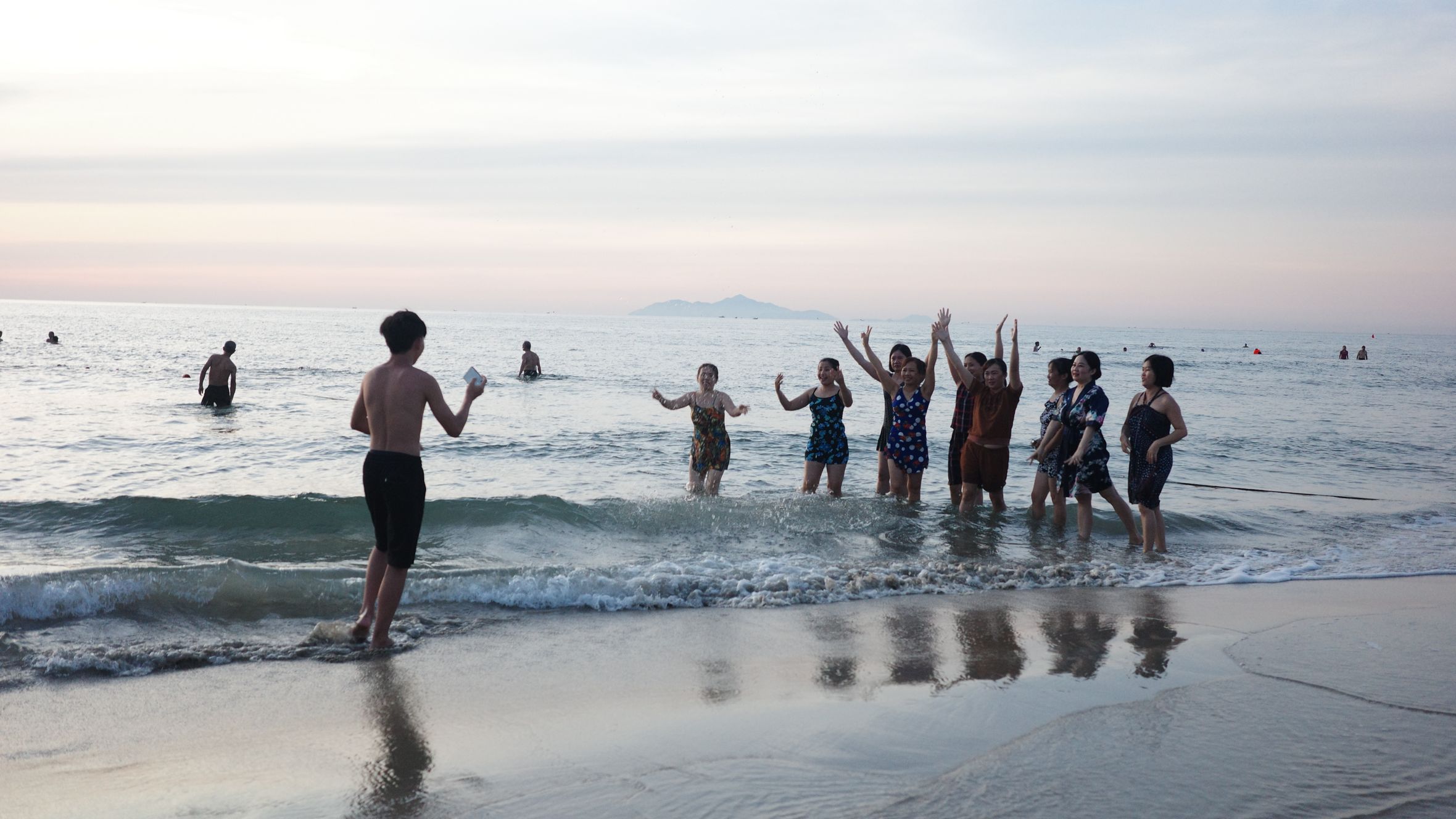 A joyful group of friends plays on the beach in Da Nang, Vietnam as the sun sets.