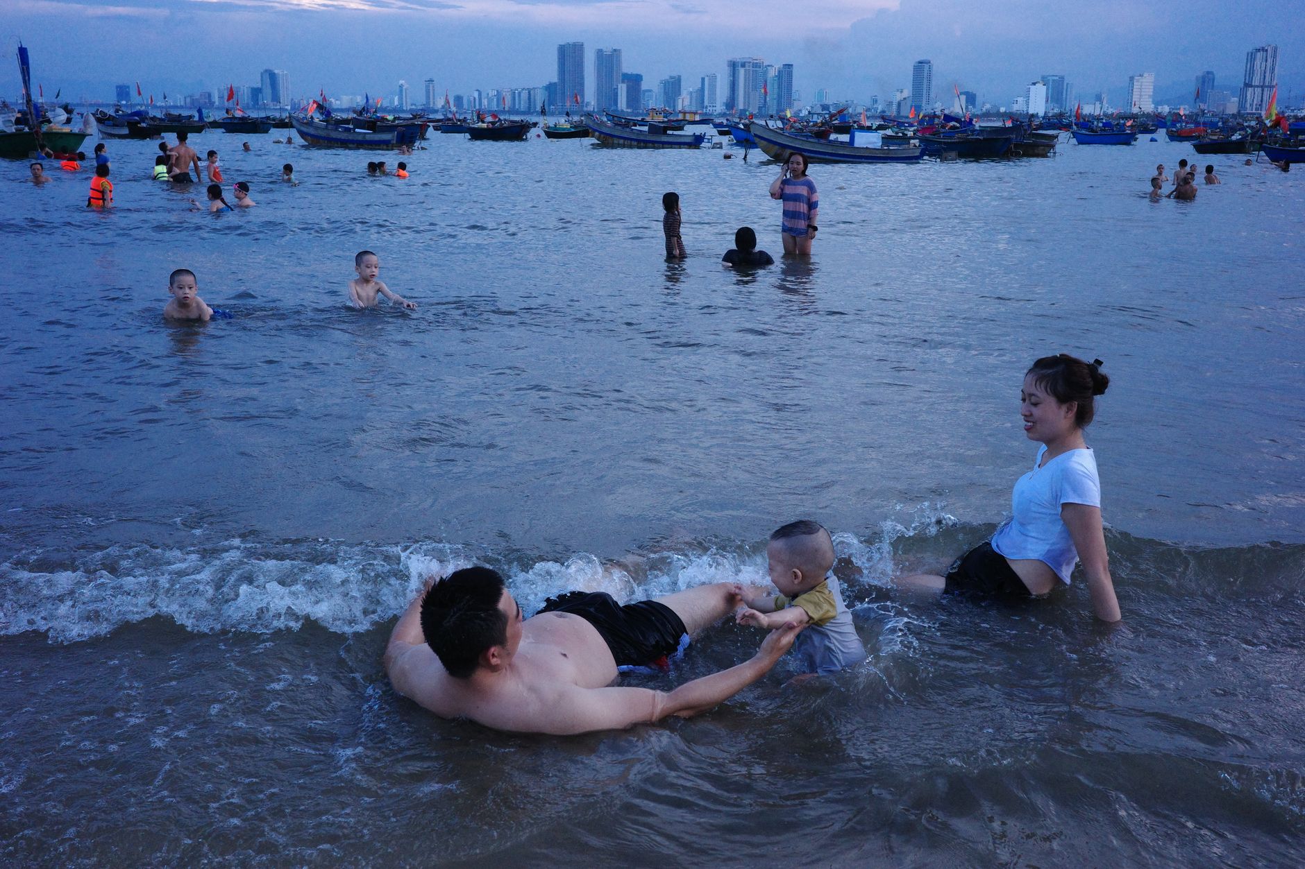 Cheerful family playing by the sea with city skyline in Da Nang, Vietnam.