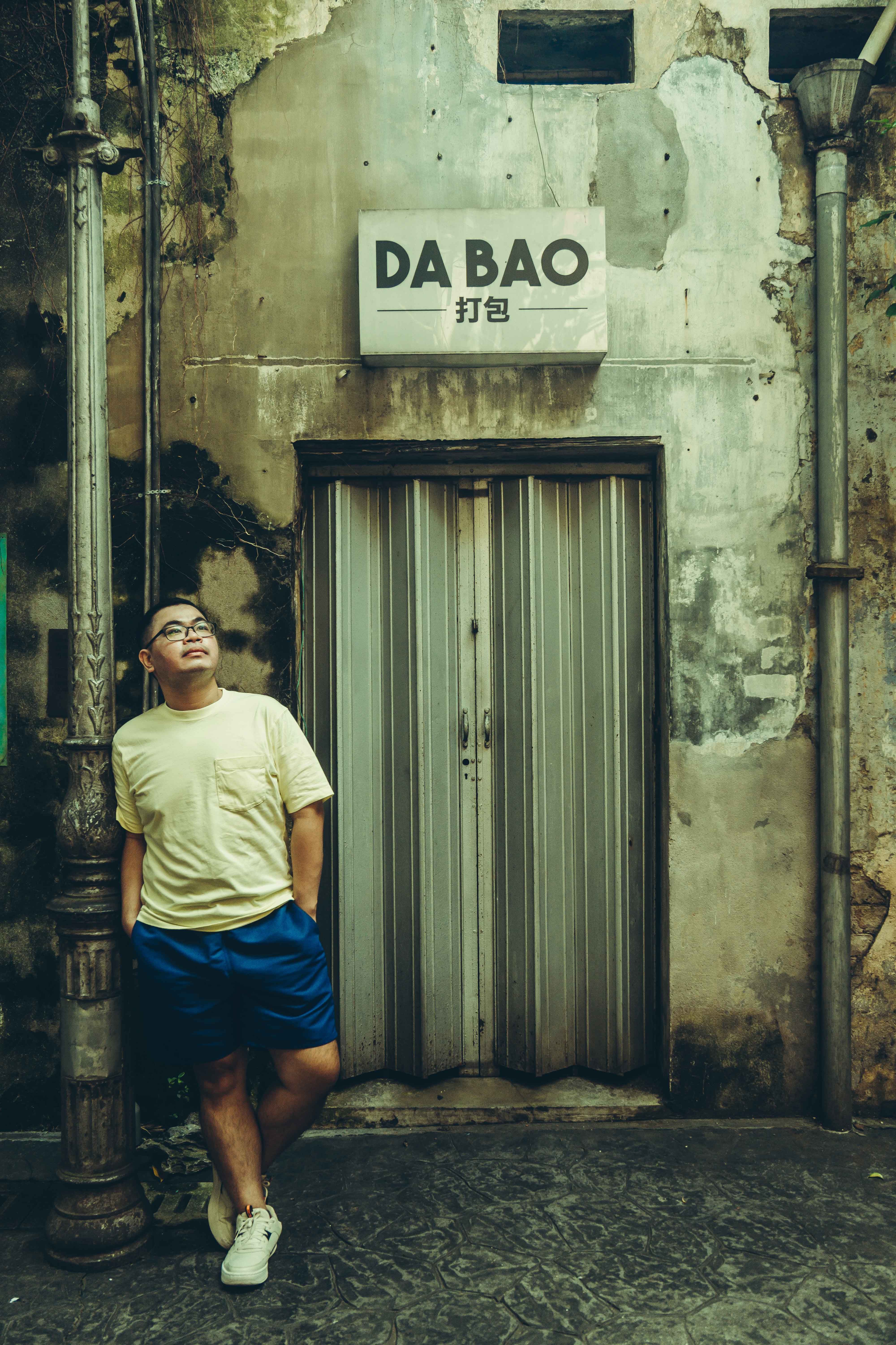 A man leans against a post near a textured urban entrance in Kuala Lumpur, Malaysia.
