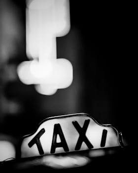 Close-up of a classic taxi sign at night in a city environment, black and white photo.