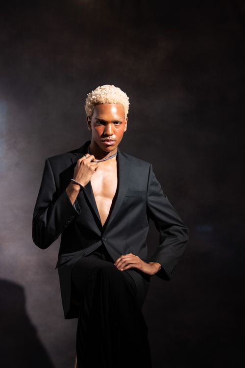 Free Elegant studio portrait of a man in a black blazer, striking a confident pose. Stock Photo