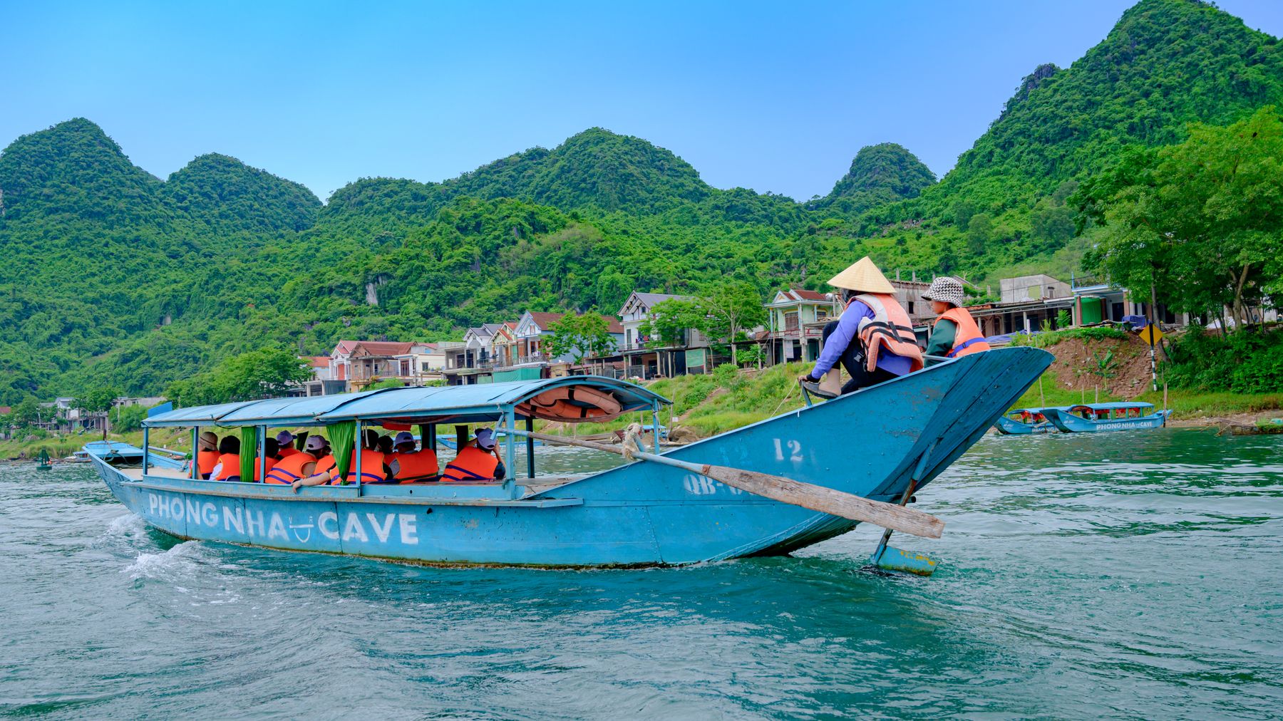 Tourists enjoy a scenic boat ride in Phong Nha Ke Bang National Park, showcasing vibrant landscapes.