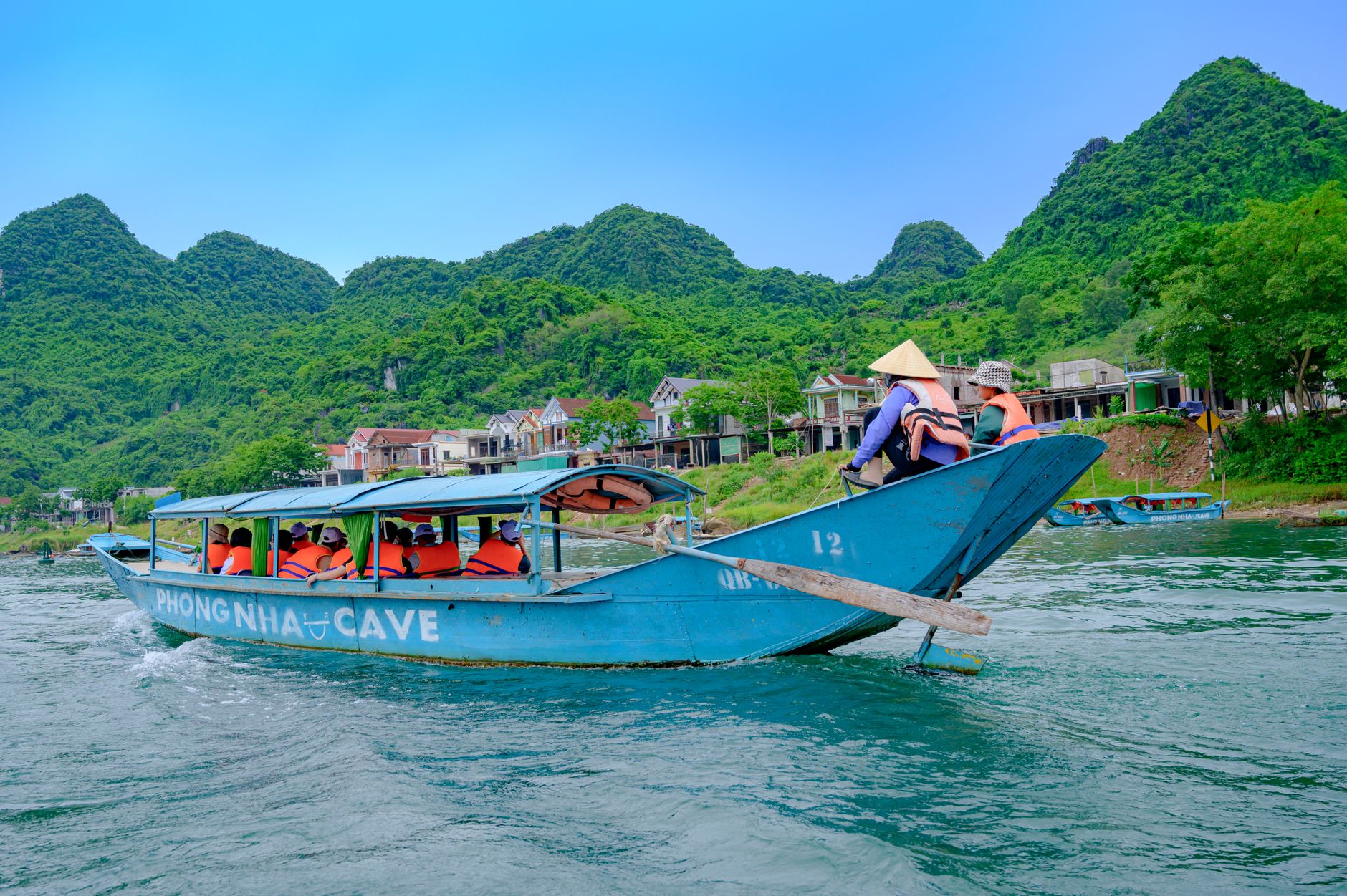 Tourists enjoy a scenic boat ride in Phong Nha Ke Bang National Park, showcasing vibrant landscapes.