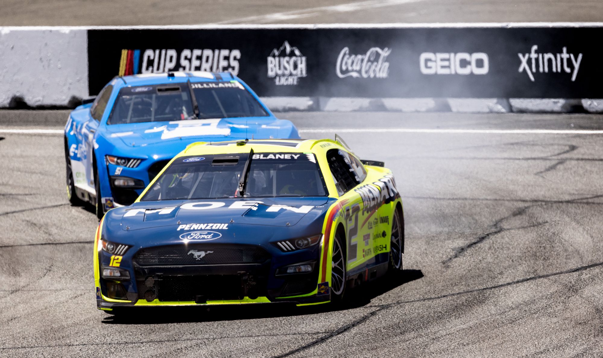 Shows NASCAR Cup Series cars racing on track with visible tire smoke, directly evoking the sensory drama the section…