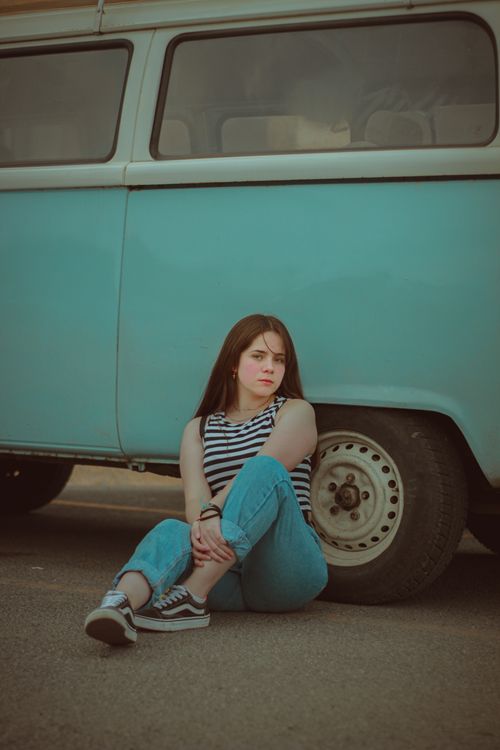 Free Young woman in casual attire sitting by a vintage van, exuding retro vibes. Stock Photo
