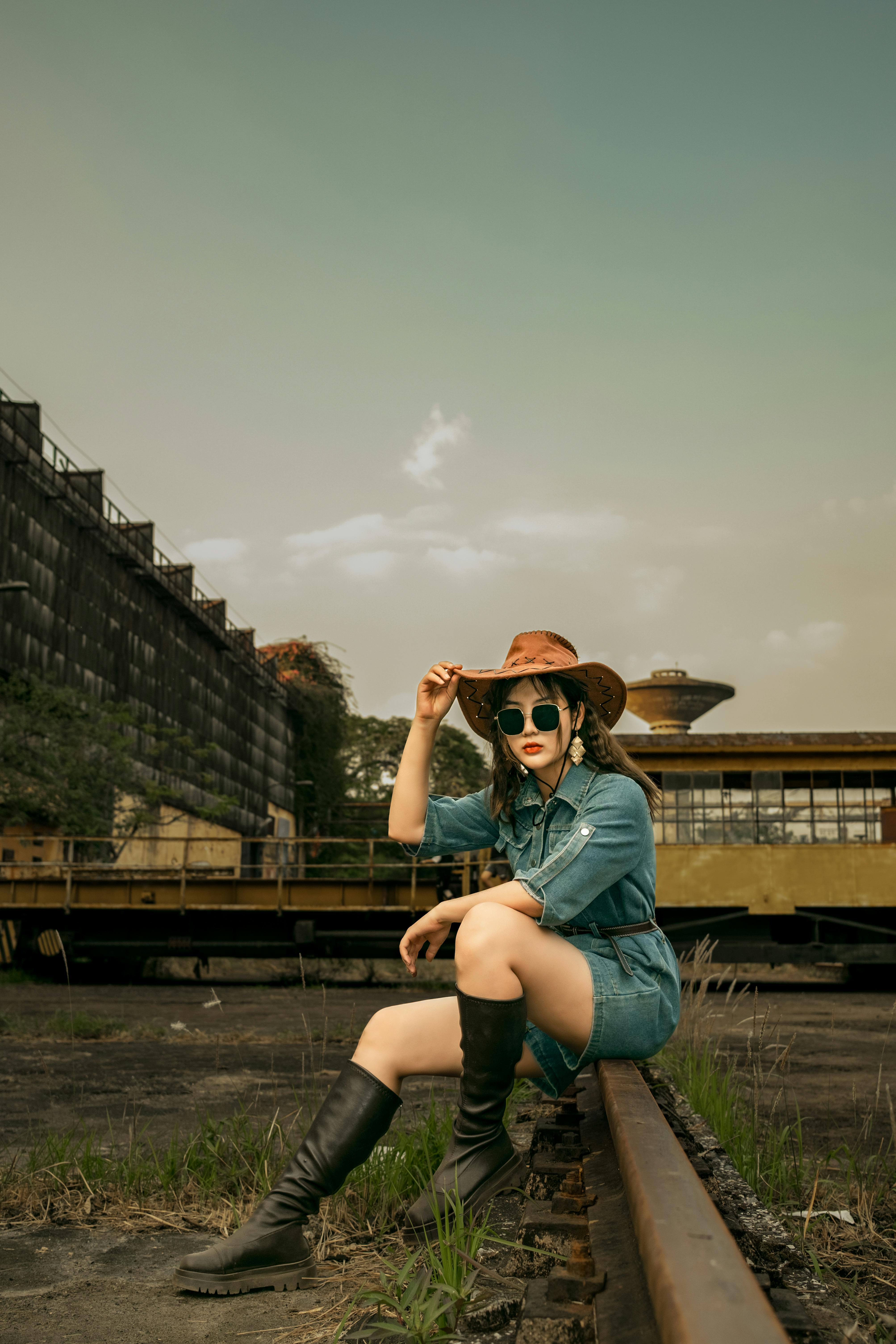 Stylish model in denim and boots posing in an industrial urban setting. Fashion meets city vibe.