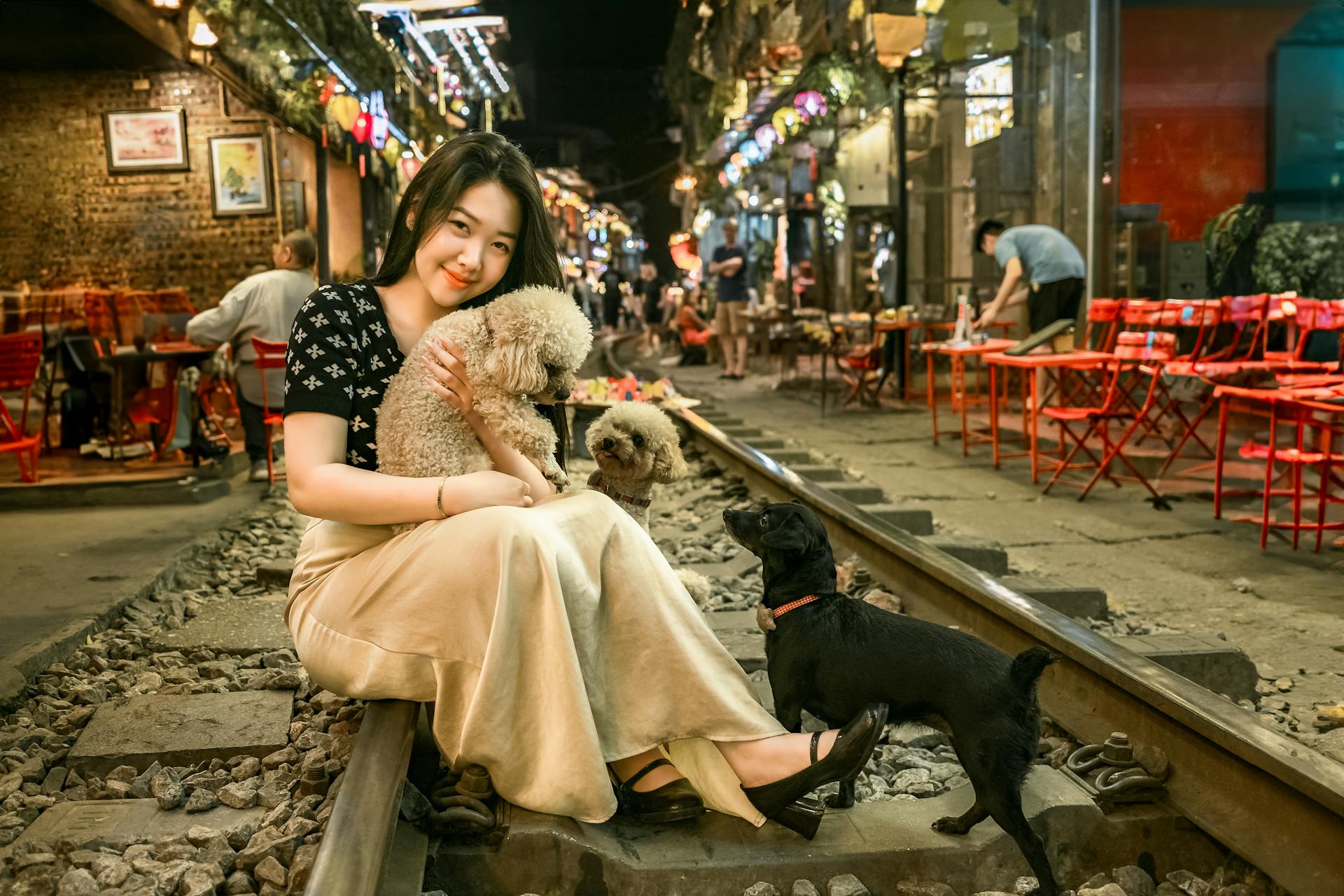 Een jonge vrouw zit met honden op de treinstraat van Hanoi