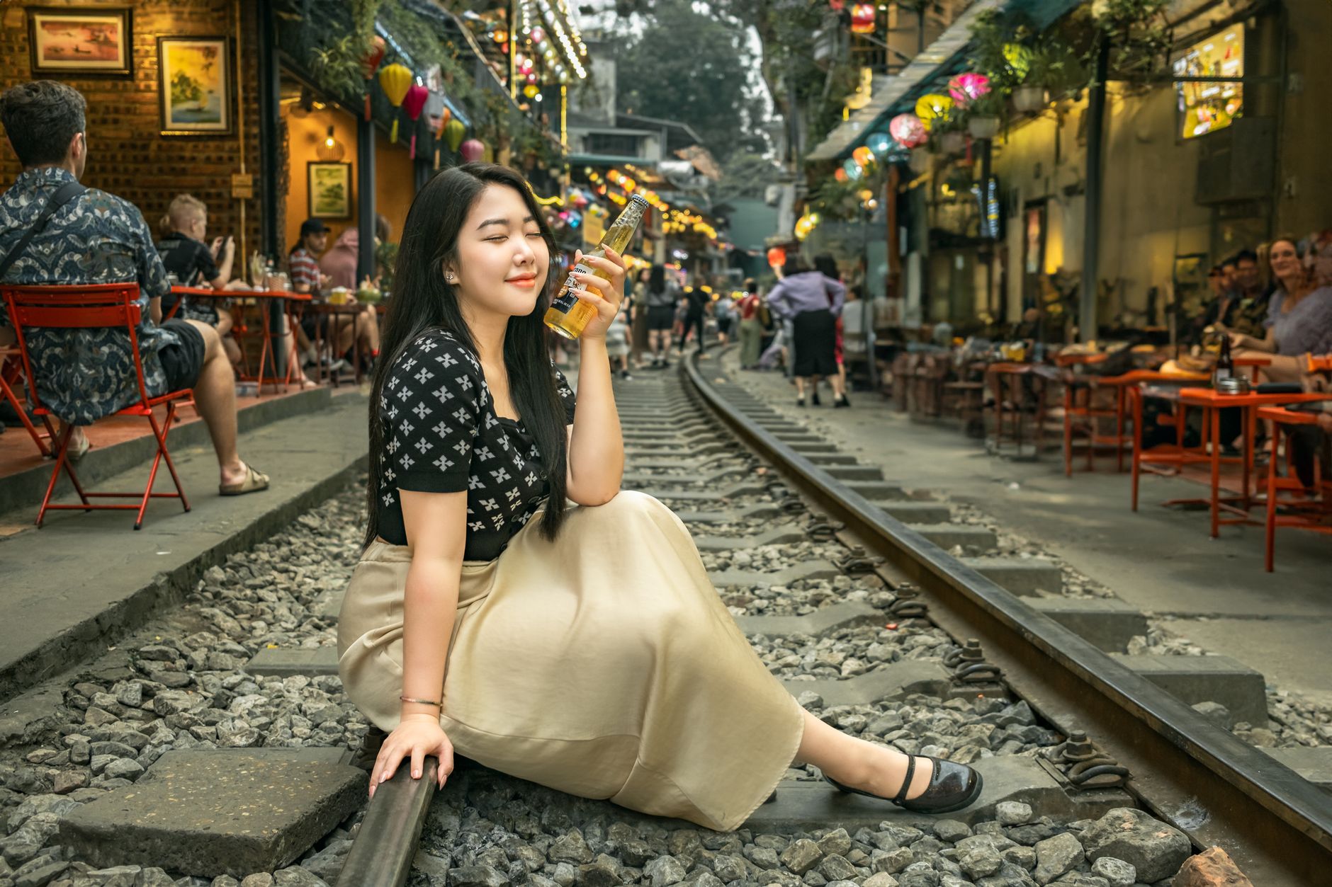A woman enjoying a drink while sitting on train tracks in Hanoi's vibrant train street.