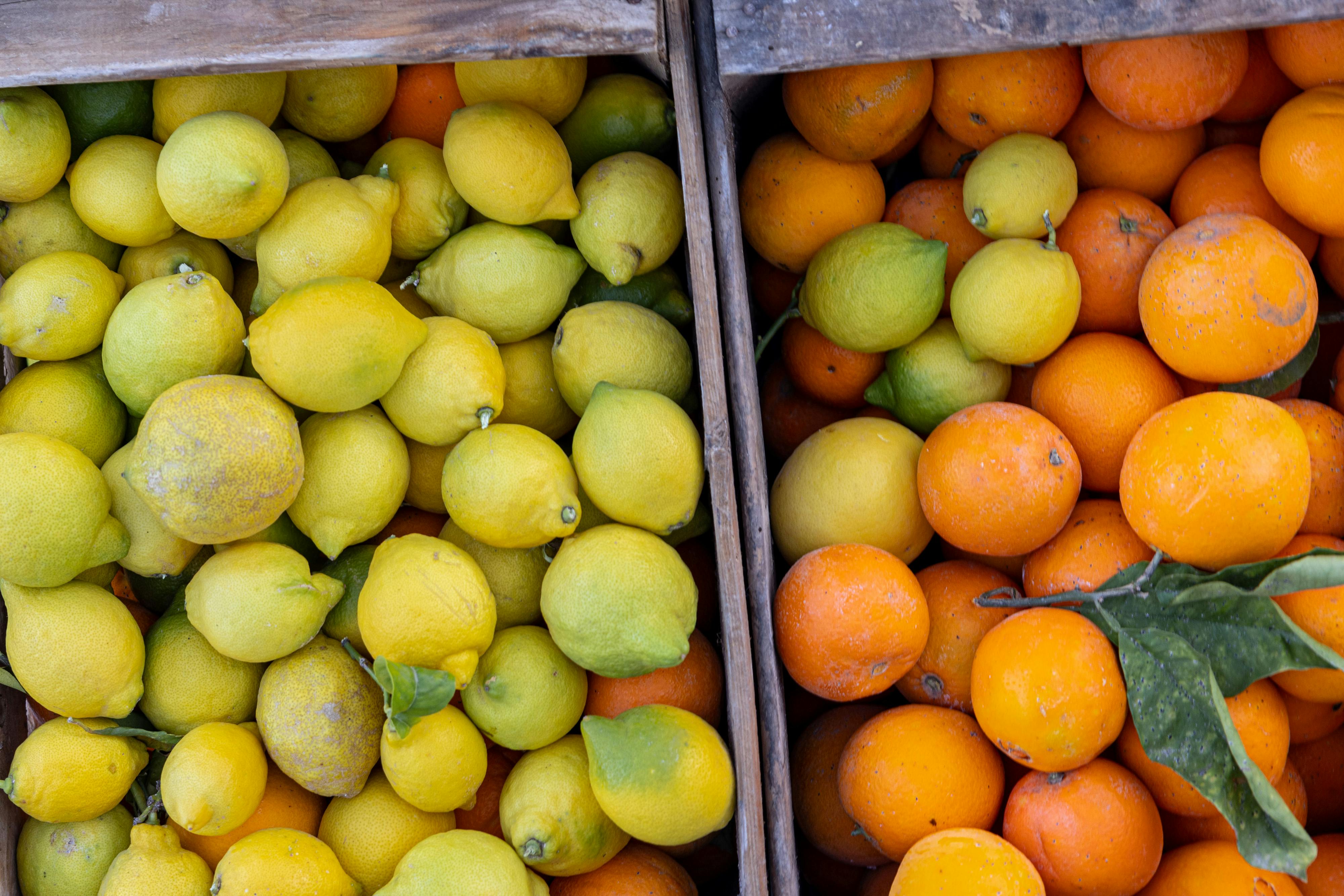 Vibrant close-up of fresh lemons and oranges in wooden crates at a market.