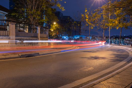 Long exposure of a city street at night showcasing colorful light trails and urban architecture.