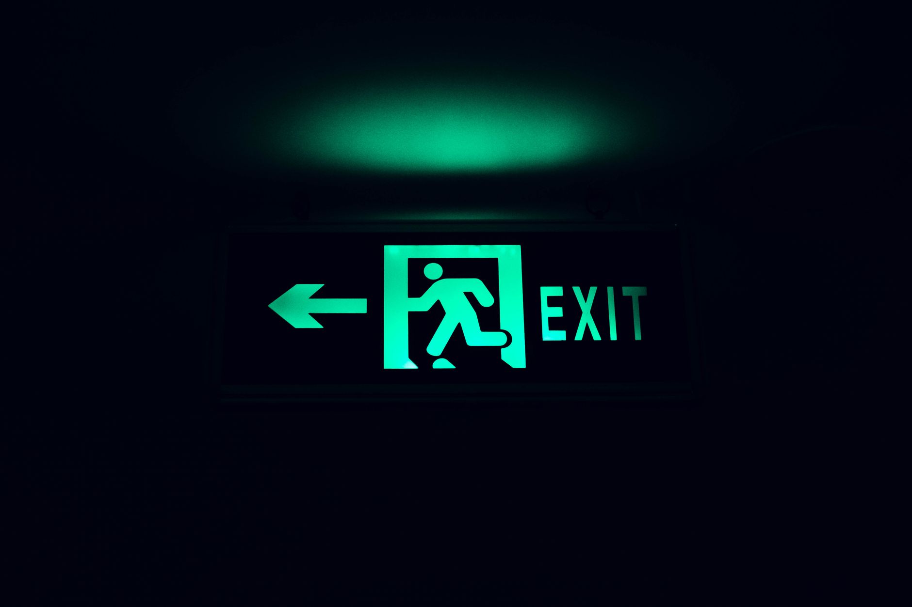 A glowing green exit sign with an arrow, guiding direction in low light.
