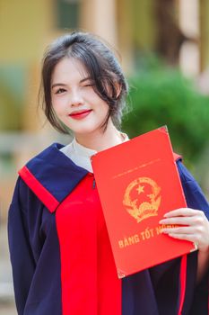 Confident young woman celebrating her university graduation outdoors.