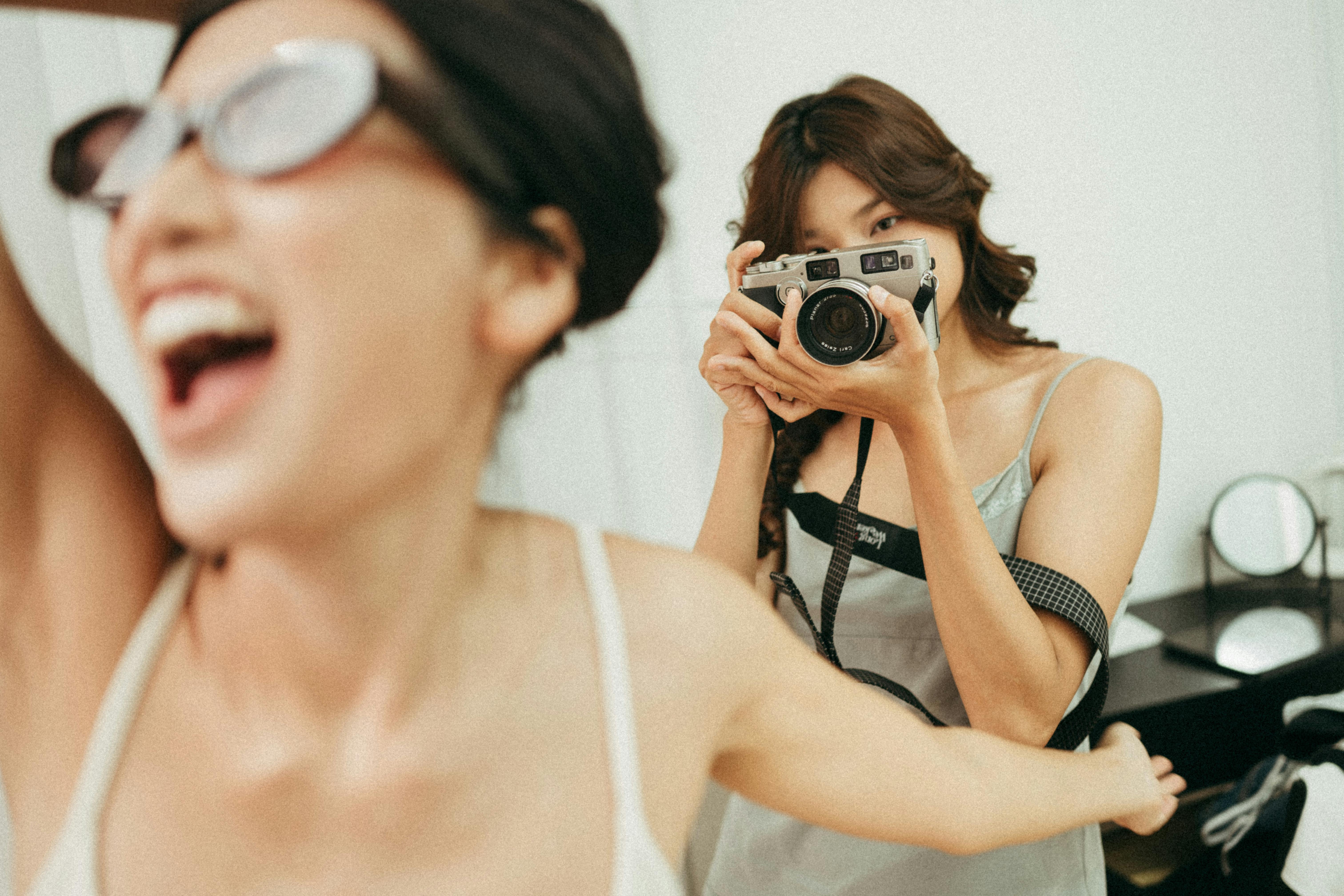 Two women enjoying a fun indoor photo shoot with an analog camera.