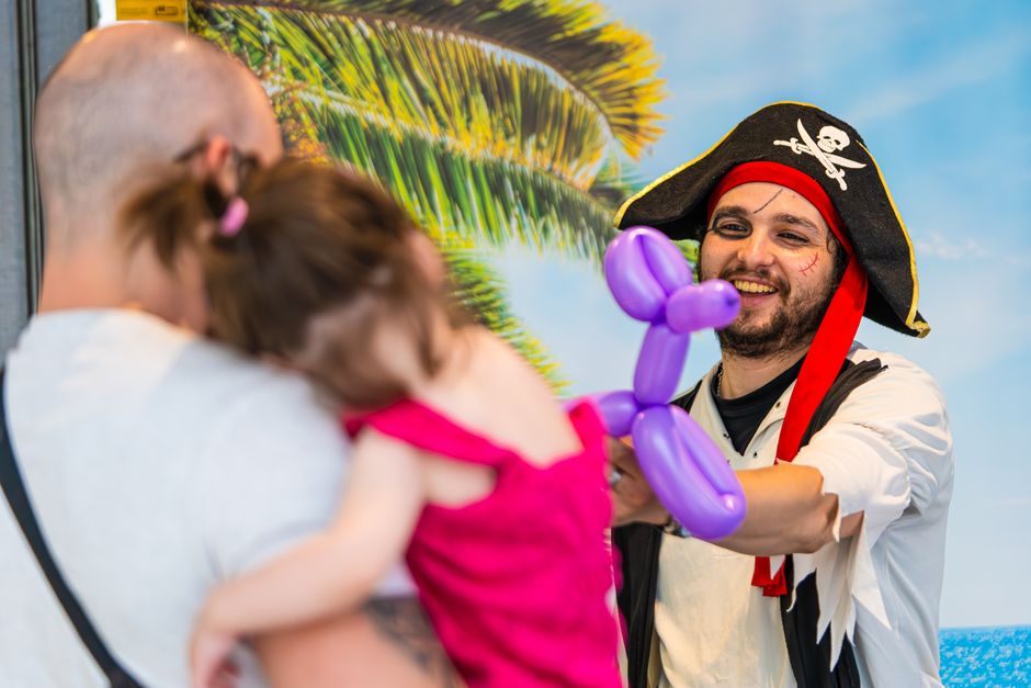Pirate entertainer gifting a balloon animal to a little girl during a fun outing.