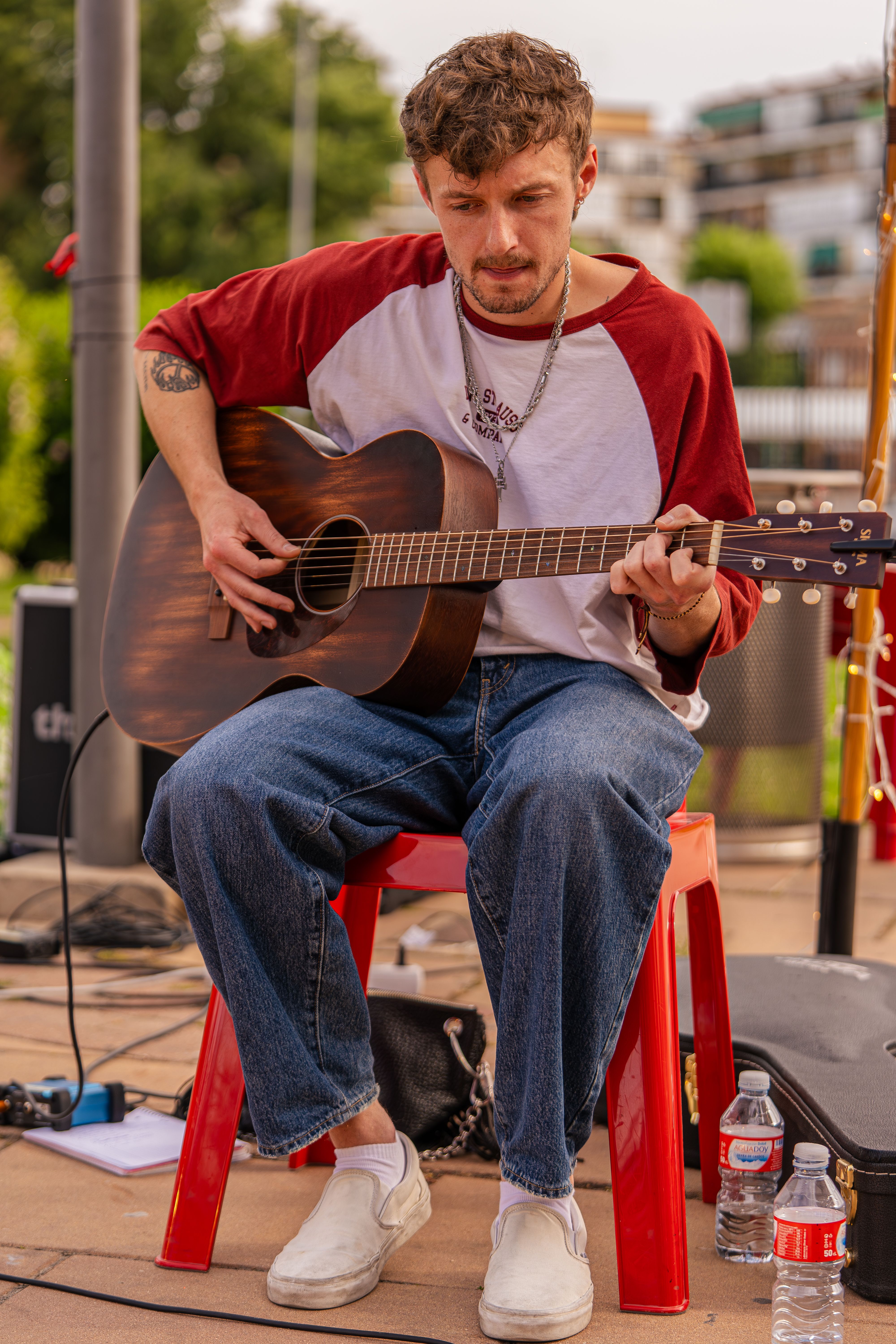 Young Man Sitting on Chair Playing Guitar on Stage · Free Stock Photo