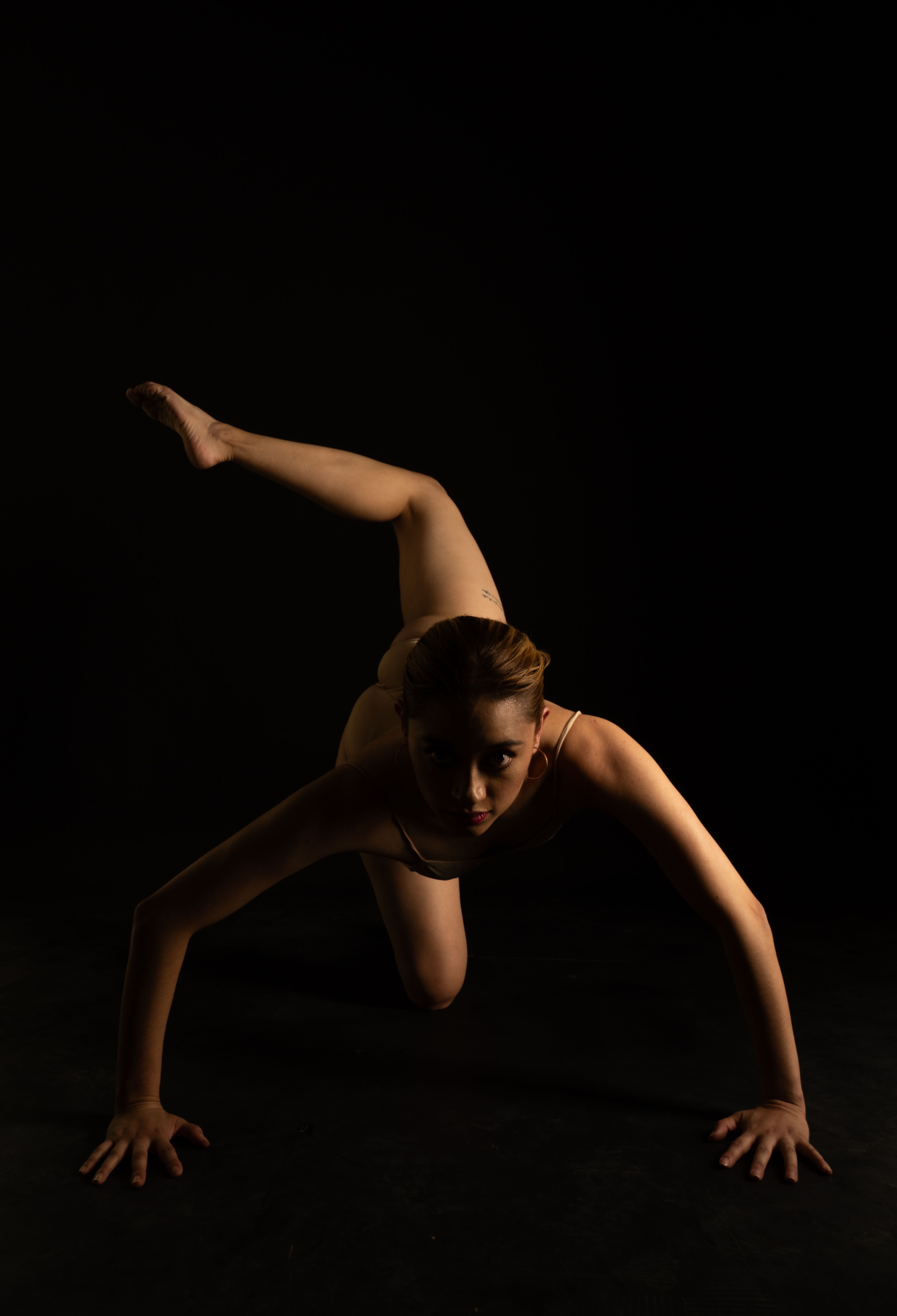 Dancer Performing a Low Pose on a Dark Stage · Free Stock Photo