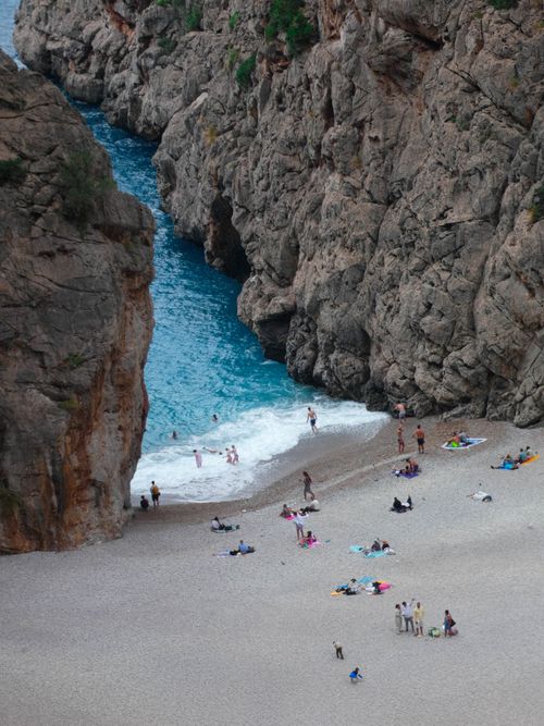 Free Stunning aerial view of a vibrant beach nestled between towering cliffs, capturing summer relaxation. Stock Photo