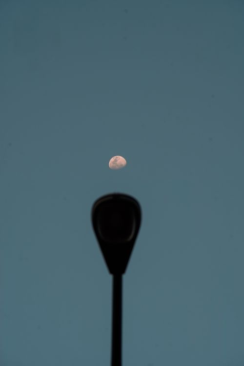 Free A street lamp silhouetted against a rising moon in a clear night sky in Cirebon. Stock Photo