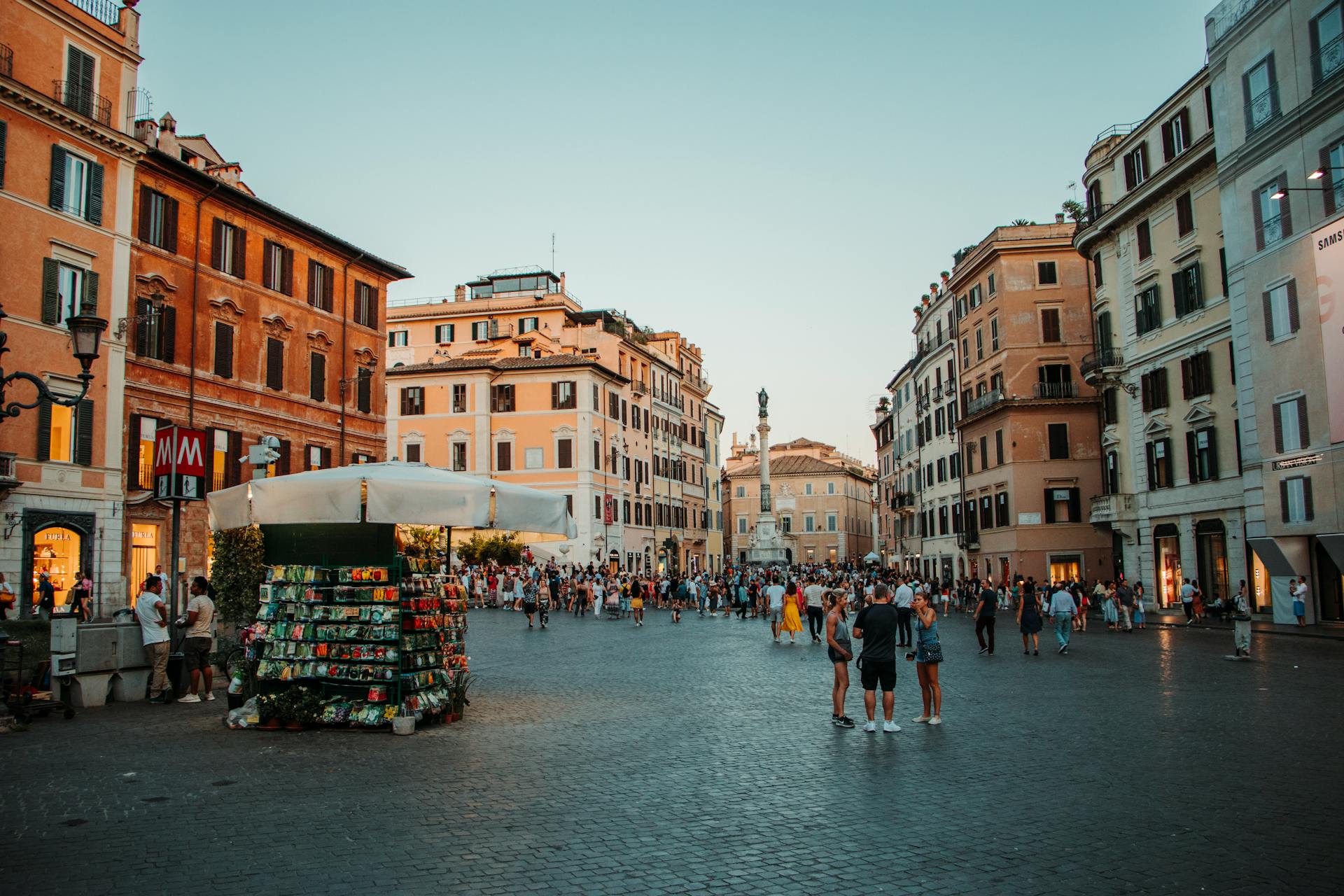 Lively urban square filled with tourists amidst historic buildings and vibrant marketplace.