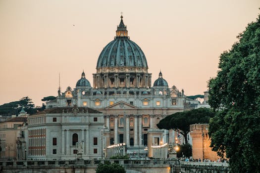 A stunning view of St. Peter's Basilica with a warm sunset backdrop in Vatican City.