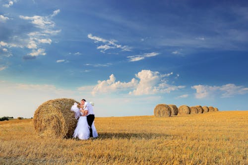 Photo of Couple Kissing Beside Hay Roll