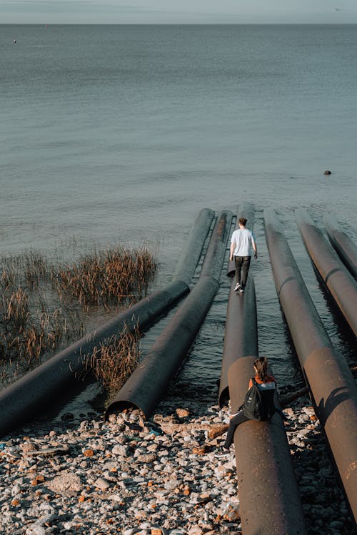 A man standing on a pier next to pipes