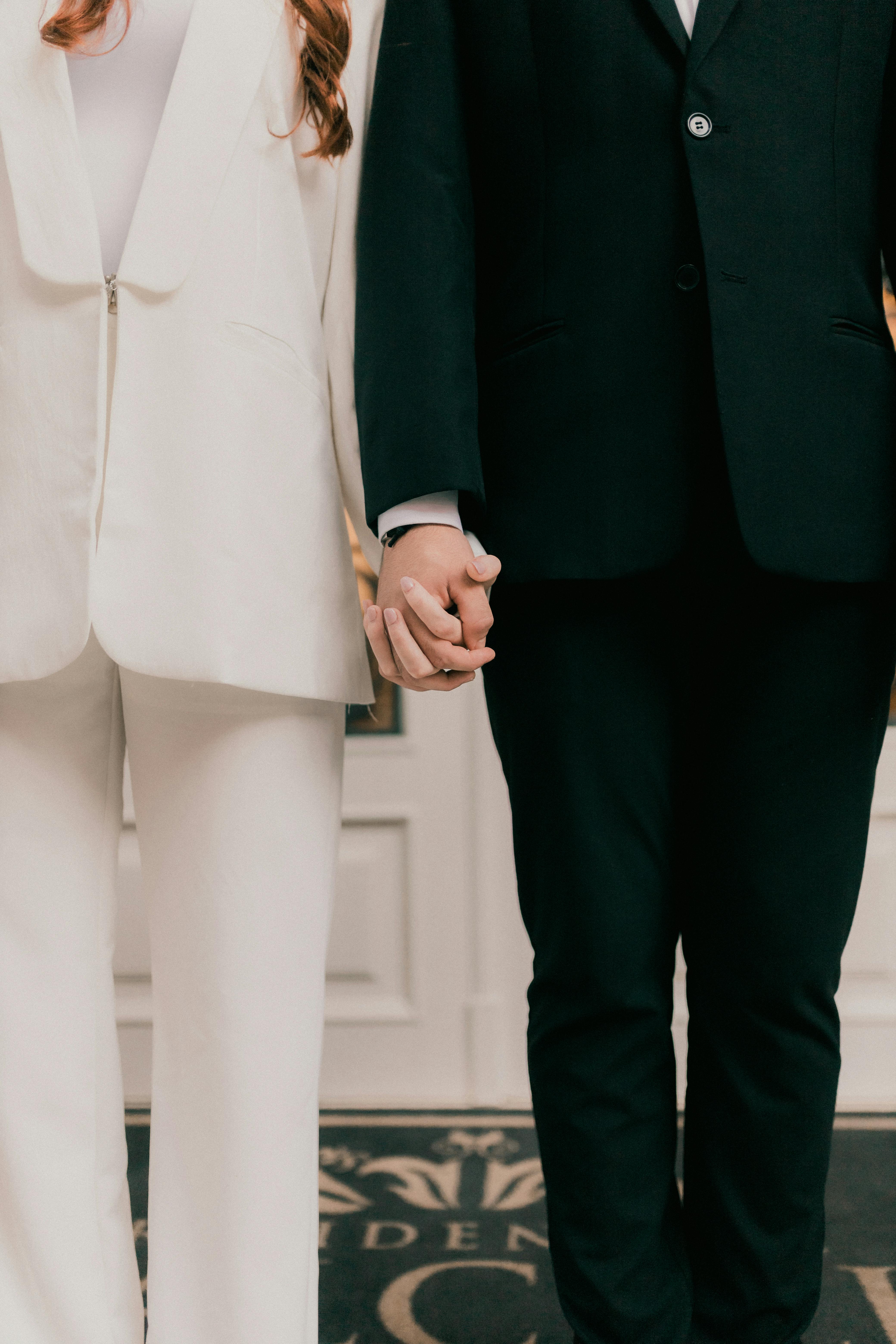 A close-up of a couple holding hands in elegant wedding attire, symbolizing love and connection.