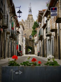 Explore a quaint historic street lined with stone buildings in a Portuguese town, perfect for travel lovers.