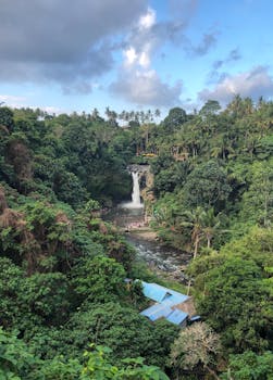 风景如画的热带瀑布在郁郁葱葱的绿色植物和蓝天的映衬下，层叠于乡村环境中