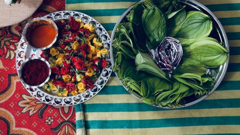 Vibrant display of fresh leaves and flower petals used in traditional ceremonies on a striped background.