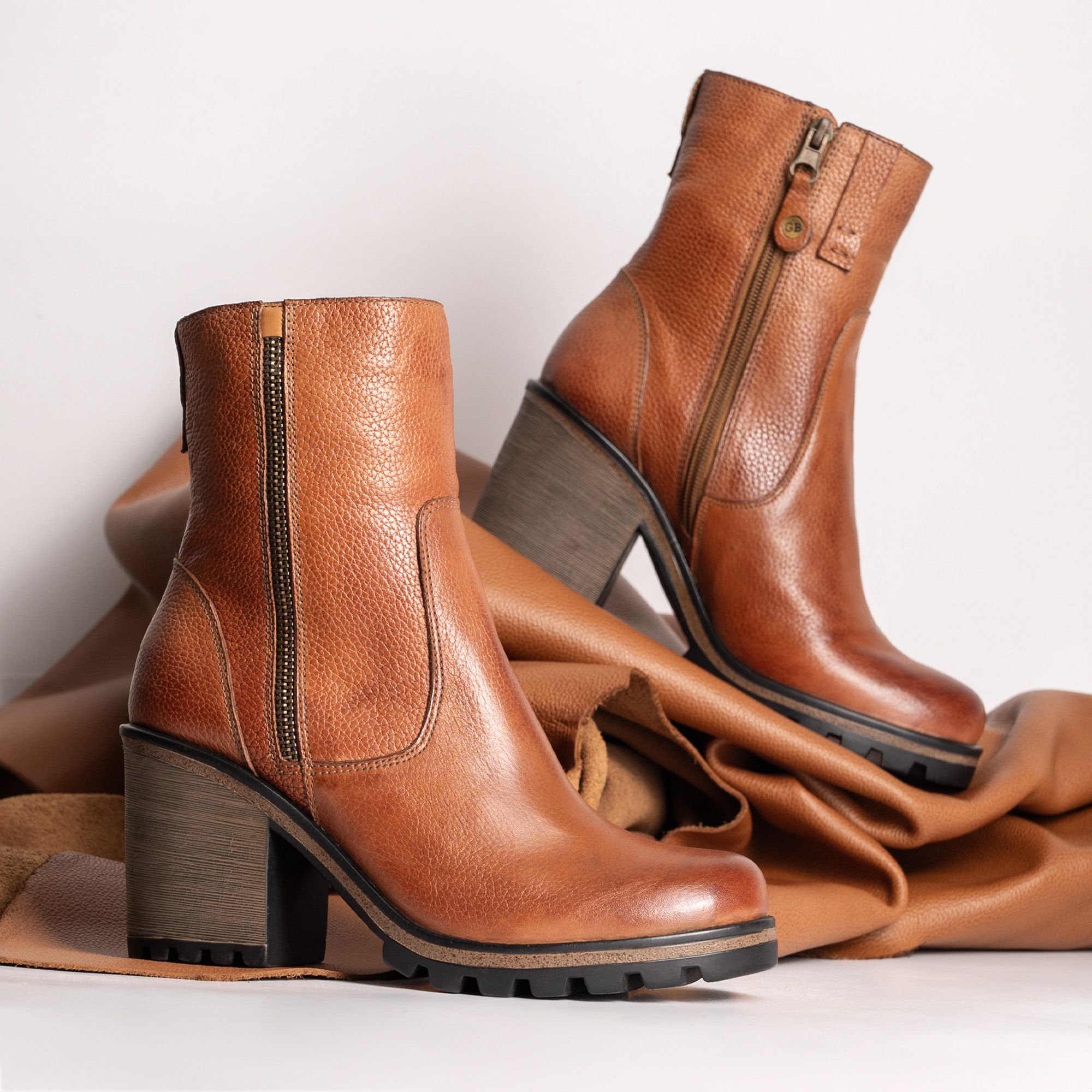 Elegant fashion photography featuring brown leather ankle boots with block heels.