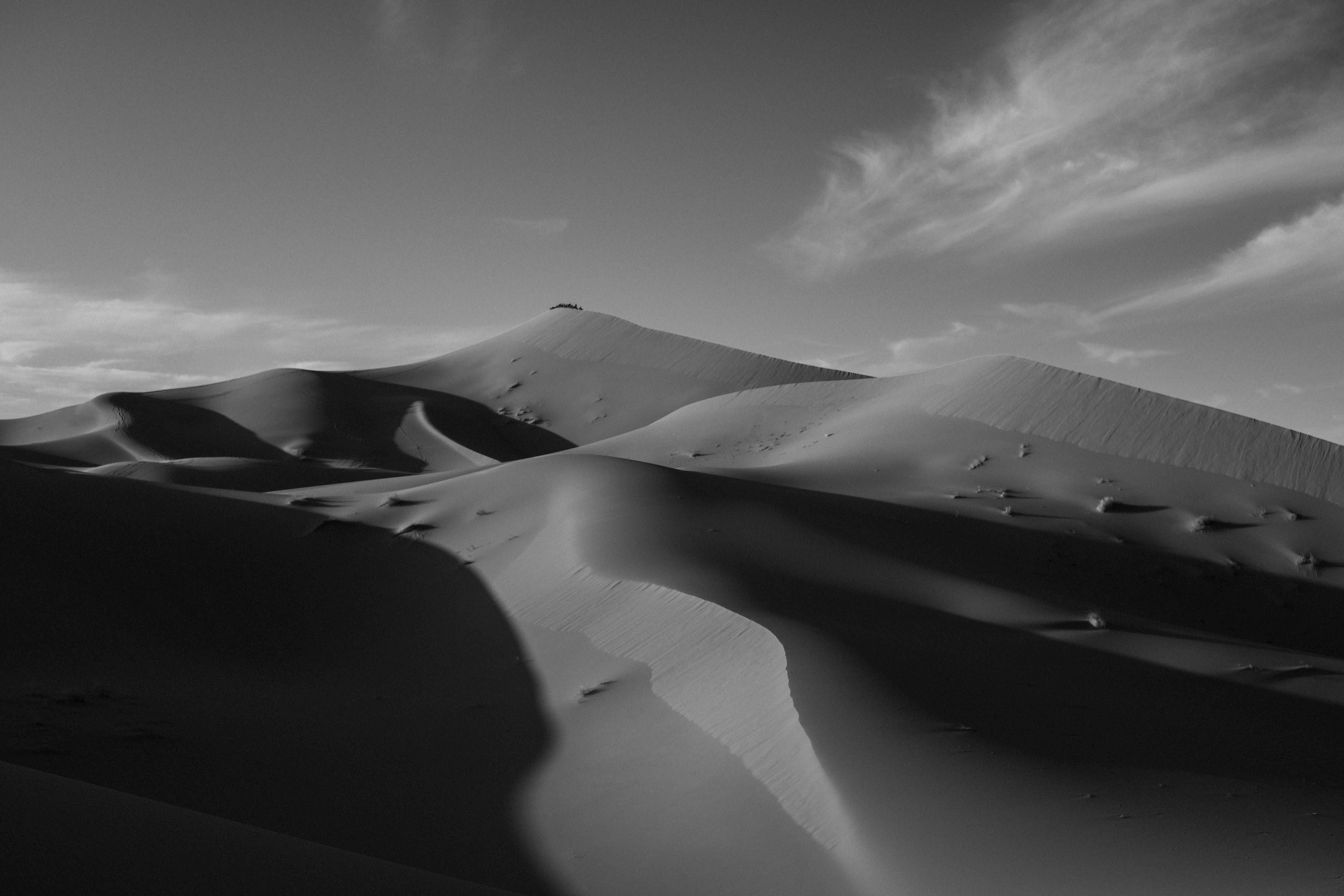 A stunning black and white photograph of desert dunes with dramatic lighting and shadows.