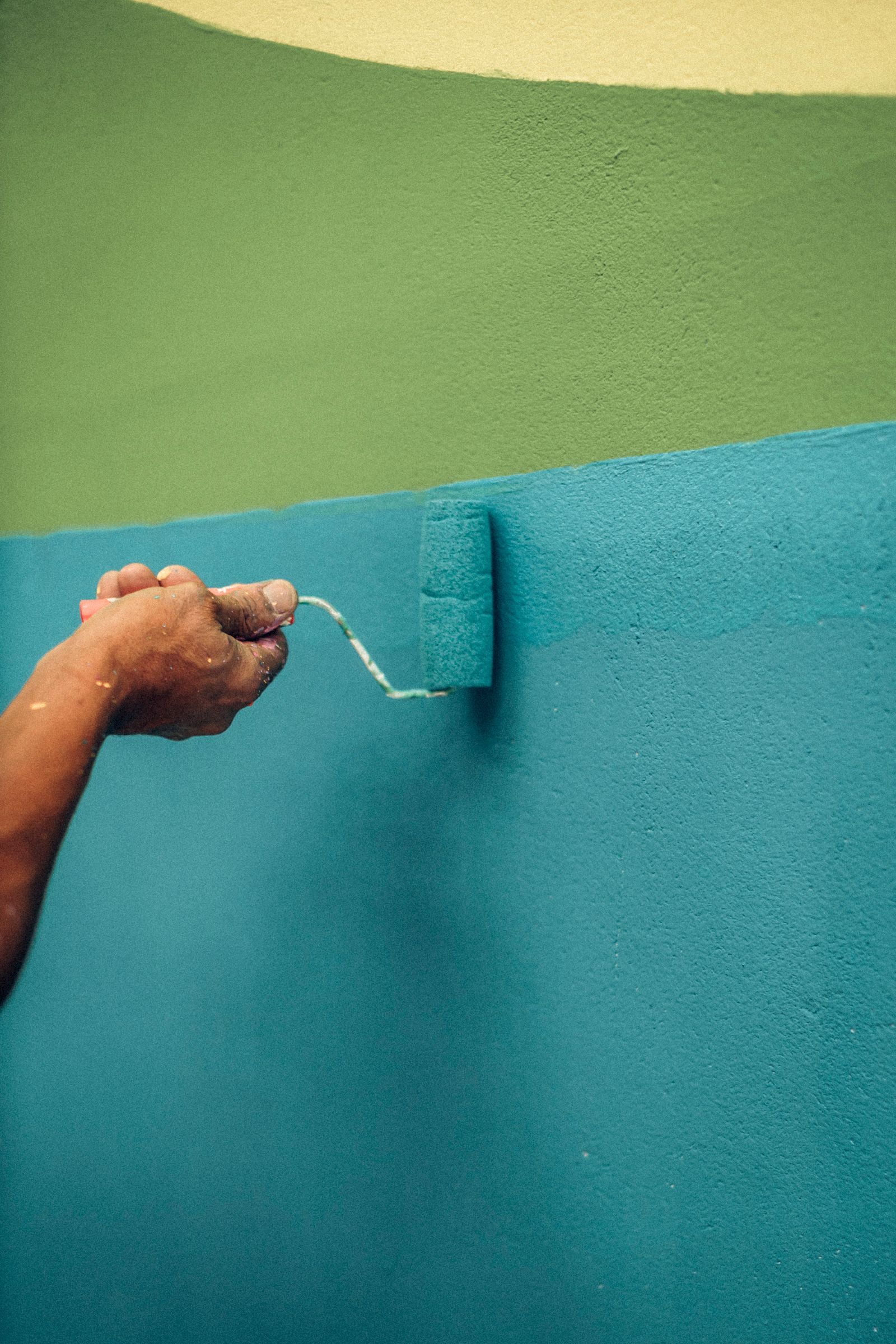 Hand using a roller to paint a wall — Why Is a Roofer Not Showing on Google Maps Palmetto Bay?
